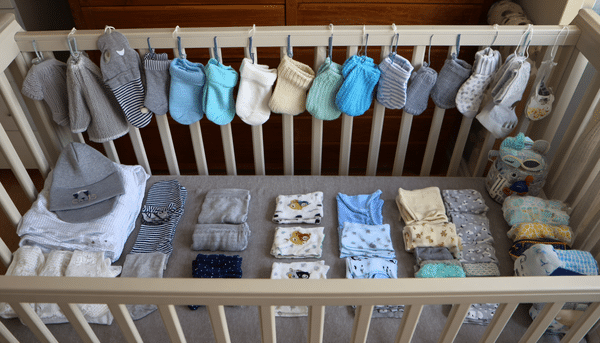 Cuna de un bebé cubierta con ropita de bebé, calcetines, gorritos, toallas, etc.