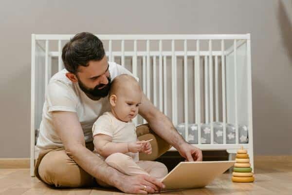 Padre e hijo sentados en el piso jugando con hojas de papel blanco y piezas de juegos didácticos de madera. Detrás de ellos una cuña blanca.